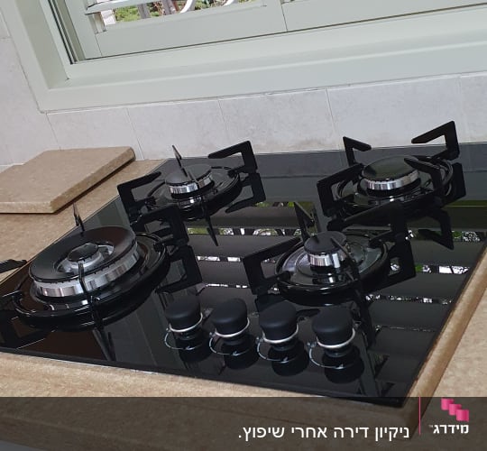 כיריים נקיות על משטח מטבח ליד חלון פתוח